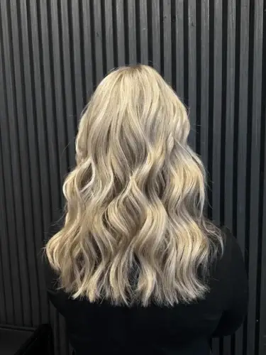 Nachher-Ergebnis einer fließenden, hellblonden Balayage mit sanften Wellen (Waves) bei Haarem Erding.
